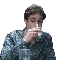 a man in a floral shirt drinks from a glass