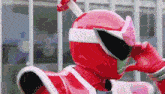 a red power ranger is talking on a cell phone while wearing a helmet .