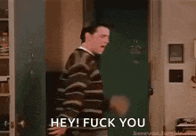 a man is standing in a doorway and saying hey ! fuck you .