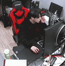 a man is sitting in a red akracing chair in front of a computer screen