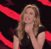 a woman wearing hoop earrings and a black shirt is laughing