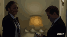 a man and a woman standing next to each other with a netflix logo on the bottom
