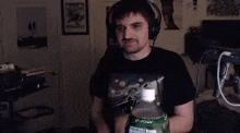 a man wearing headphones is holding a bottle of soda and making a stop sign .