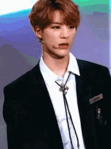 a young man in a suit and tie with the name jeno on his name tag