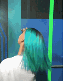 a woman with bright blue hair is standing in front of a blue wall