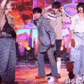a group of people are dancing on a stage with a soccer ball in the middle .