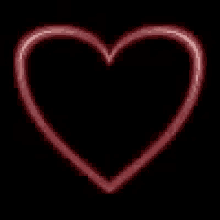 a red neon heart on a black background .