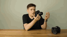 a man holds a canon camera in his hands