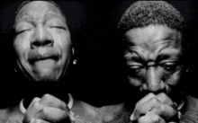 a black and white photo of a man crying and another man praying