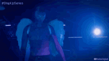 a man with angel wings is standing in a dark room with blue lights