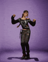 a woman in a black sweater and black pants is standing on a purple background
