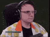 a man wearing headphones and glasses is sitting in a chair with a microphone .