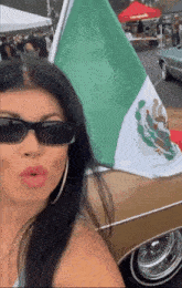 a woman is holding a mexican flag in front of a car .
