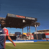 a toyota stadium with a man walking in front of it