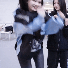 a blurry picture of two girls dancing with one wearing a blue jacket that says ' a ' on it