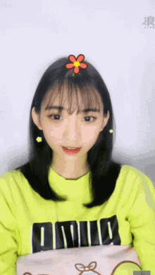 a girl with a flower in her hair is wearing a yellow shirt that says pink