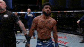 a man with a tattoo on his chest is standing in a ufc ring