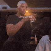 a man in a black shirt is standing in front of a group of people and making a funny face .