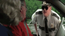 a police officer wearing sunglasses is talking to a man in a car