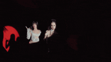 two women are standing next to each other in the dark with a red light behind them