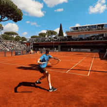 a tennis player in a blue shirt is playing on a red court