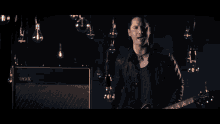 a man playing a guitar next to a vox amplifier