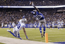 a new york giants player catches a football while a cowboys player tries to block him