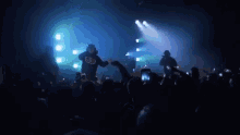 a group of men are standing on a stage in front of a crowd of people .