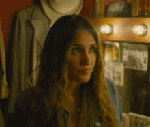 a woman in a blue shirt stands in front of a mirror with a picture of a man on it