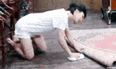 a woman is kneeling on the floor and cleaning a rug .