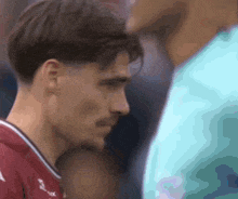 a close up of a soccer player 's face while standing next to another soccer player .