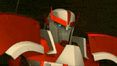 a close up of a robot with red and white armor and blue eyes
