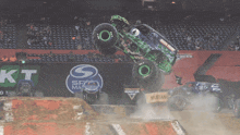 a monster truck is jumping in the air in front of a mustang advertisement