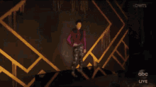 a woman in a purple jacket is standing in a dark room with a spotlight in the background .