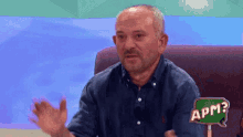 a man sitting on a couch with a sign that says apm