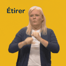 a woman in a blue cardigan is making a sign that says etirer