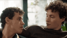 a couple of men with curly hair are looking at each other