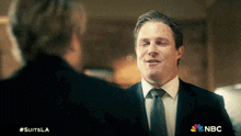 a man in a suit and tie is talking to another man in a suit