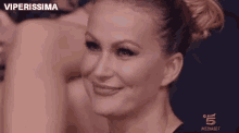 a woman is smiling and looking at the camera while sitting in front of a group of people .