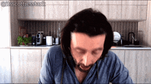 a man with long hair and a beard is sitting in a kitchen with the hashtag @itsscottiesstark on the bottom