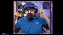 a man with a beard wearing headphones and a blue shirt with the north face on it