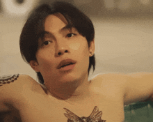 a shirtless man with a tattoo on his chest is looking at the camera