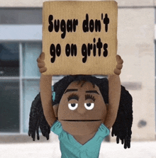 a puppet holding a sign that says sugar don t go on grits