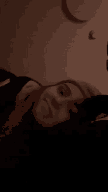 a woman is laying on a bed with her head on a pillow and making a funny face .