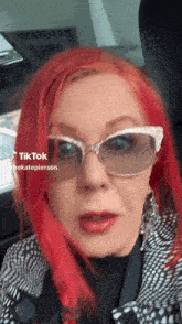 a woman with red hair is wearing sunglasses and a black and white coat