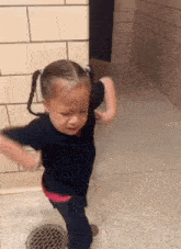 a little girl with pigtails is crying in a hallway next to a drain
