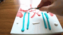 a person is painting red white and blue lines on a white surface