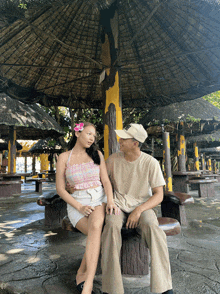 a man and a woman sit under a thatched roof