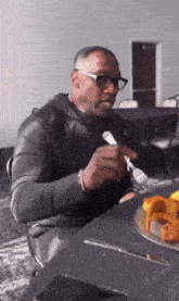 a man is sitting at a table eating a plate of food with a fork .