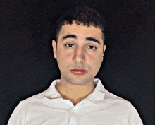 a man wearing a white shirt looks at the camera with a black background